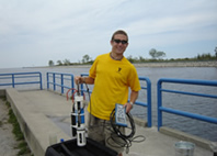 Eric Strickler holds a water quality sonde near the Muskegon Lake Channel